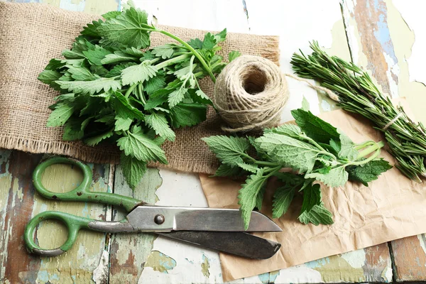 Leaves of lemon balm and rosemary sprigs with rope and scissors on wooden table, closeup — Stock Photo, Image