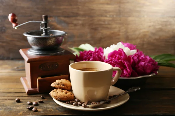 Kompozycja z, młynek do kawy, filiżanka kawy i piwonia kwiat na drewniane tła — Zdjęcie stockowe