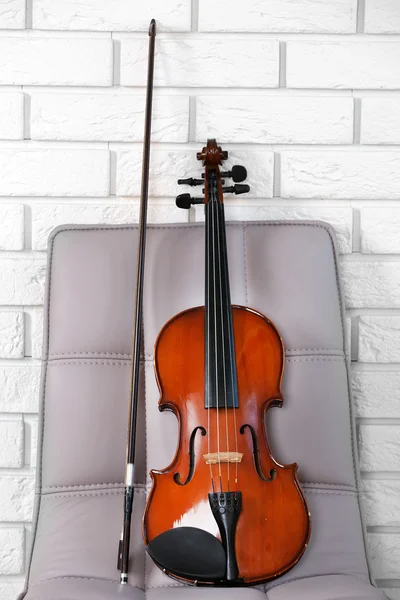Geige auf Stuhl, auf Ziegelwand Hintergrund — Stockfoto