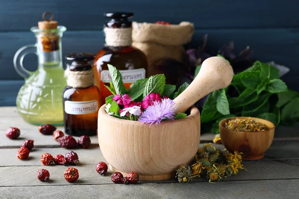 Ervas, bagas, flores e pílulas na cor de fundo mesa de madeira — Fotografia de Stock