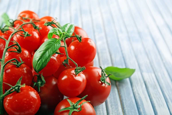 Fresh cherry tomatoes with basil on wooden table close up — Stock Photo, Image