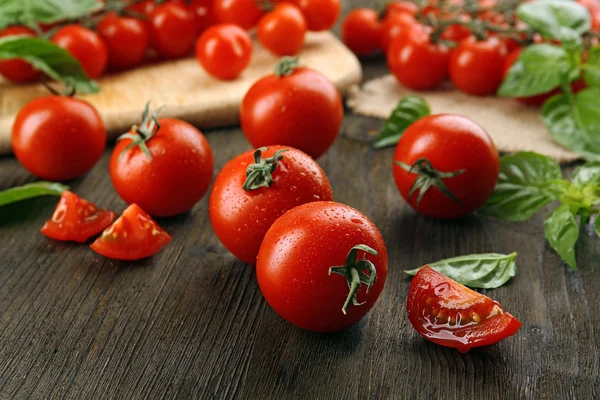 Fresh tomatoes with basil on wooden table close up — Stock Photo, Image