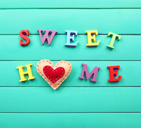 Letras decorativas formando palavras doce casa com coração sobre fundo de madeira — Fotografia de Stock