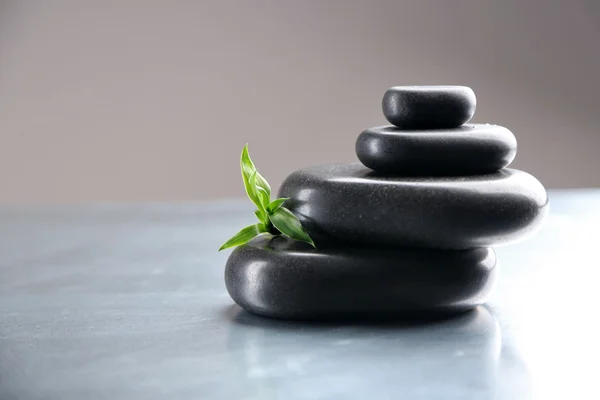 Stack of spa stones with green leaves on gray background — Stock Photo, Image