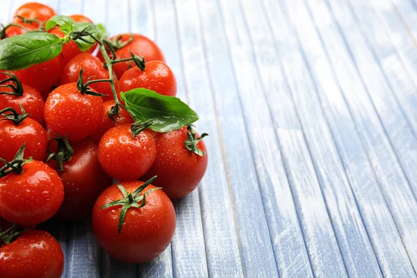 Fresh cherry tomatoes with basil on wooden table close up — Stock Photo, Image