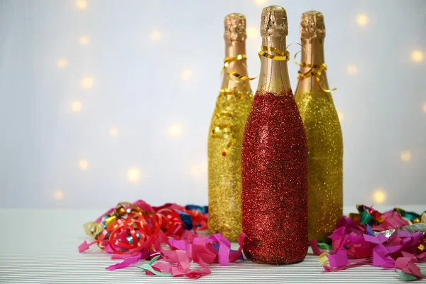 Botellas decorativas de champán con serpentina sobre fondo claro — Foto de Stock