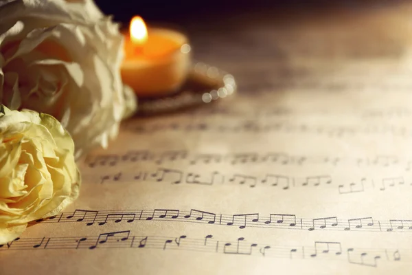 Hermosas rosas con perlas y velas en las hojas de música de fondo —  Fotos de Stock