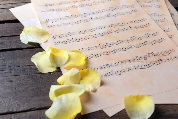 Vackra rosenblad på musik ark på träbord, närbild — Stockfoto