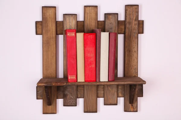 Wooden shelf with books on wall background — Stock Photo, Image