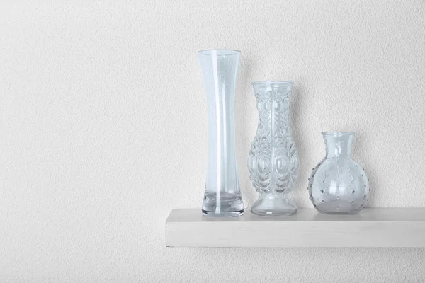 Decorative glass vases on wooden shelf — Stock Photo, Image