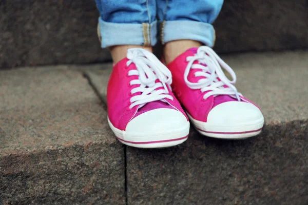 Pies femeninos en zapatos de goma rosa — Foto de Stock