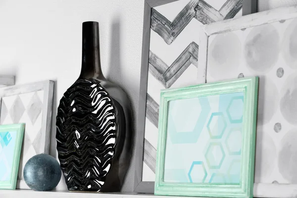 Modern vase with picture on shelf in room — Stock Photo, Image