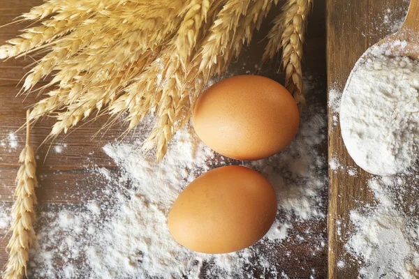 Farinha inteira com trigo e ovos em mesa de madeira, close-up — Fotografia de Stock