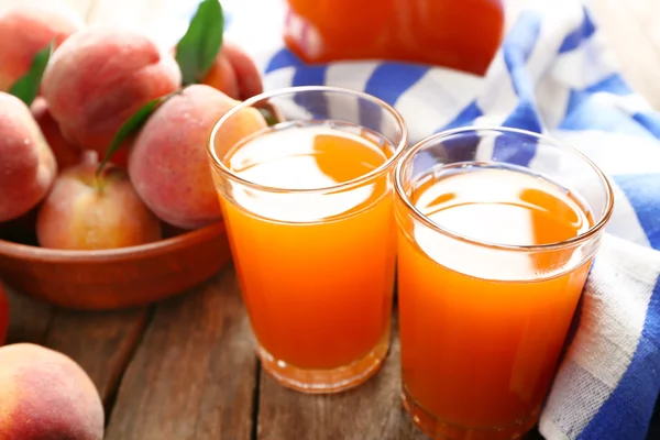 Reife Pfirsiche und Saft im Glas auf Holzgrund — Stockfoto