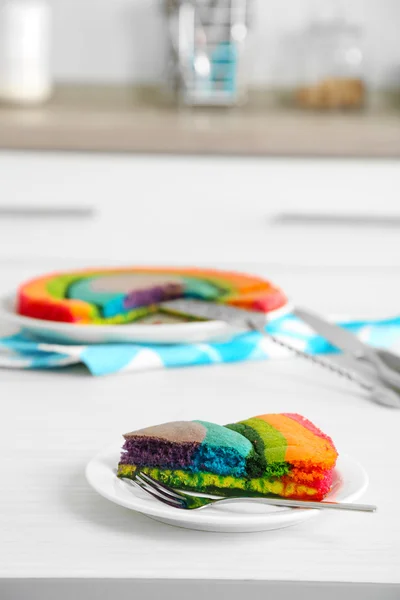 Delicioso bolo de arco-íris na placa, no fundo claro — Fotografia de Stock