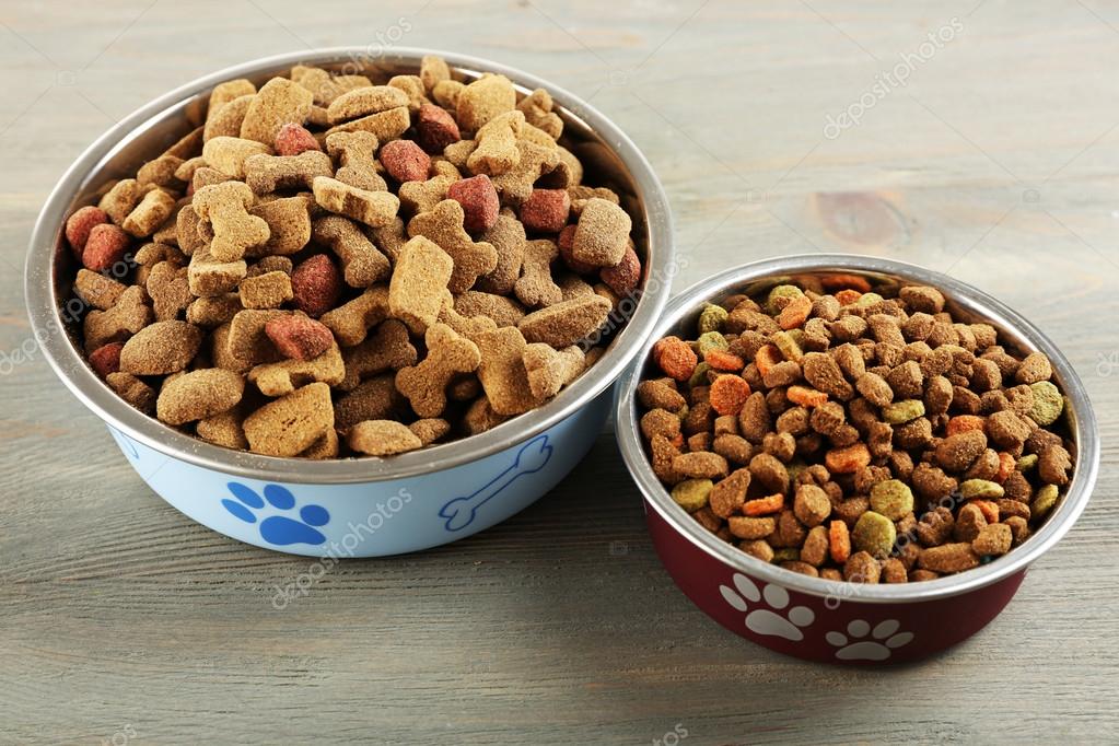 Dog food in bowls on wooden table Stock Photo by ©belchonock 79073158