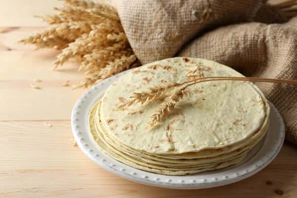 Stos domowe pszennej mąki tortilli na talerzu, na tle drewniany stół — Zdjęcie stockowe