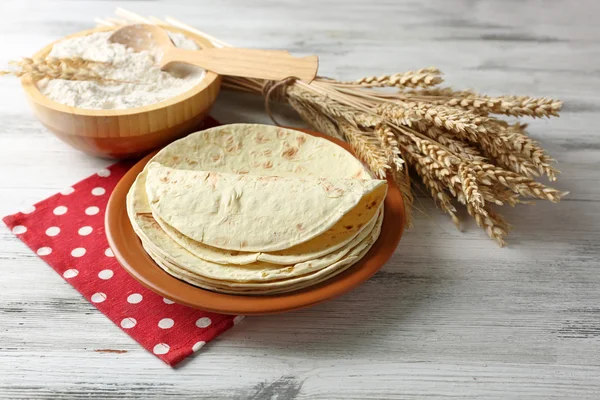 Bunt med hemgjord hela vete mjöl tortilla på plattan, på träbord bakgrund — Stockfoto