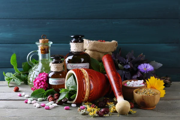 Herbs, berries, flowers and pills on color  wooden table background — Stock Photo, Image