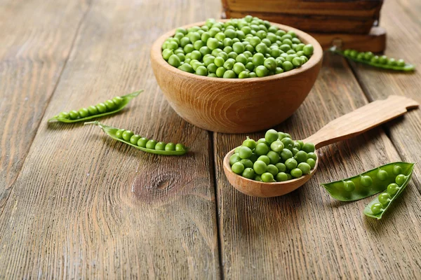 Guisantes verdes frescos en tazón y cuchara en la mesa de cerca —  Fotos de Stock