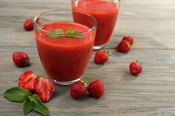 Glasses of strawberry smoothie with berries on wooden table close up — Stock Photo, Image