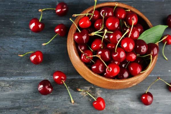 Cerises fraîches dans un bol sur fond en bois — Photo