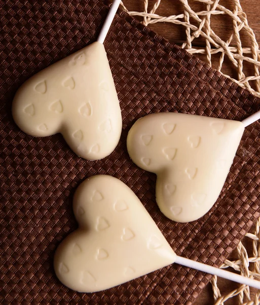 Chocolade hartvormige snoepjes op stokken op bruin servet, close-up — Stockfoto