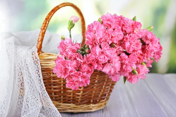 Beautiful bouquet of pink carnation in basket on bright background — Stock Photo, Image