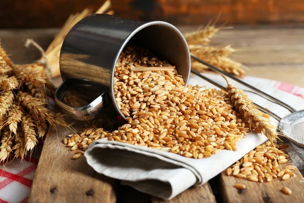 Wheat in metal cup on wooden table, closeup — Stock Photo, Image