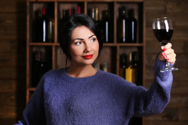 Hübsche junge Frau mit Weinglas im Weinregal — Stockfoto