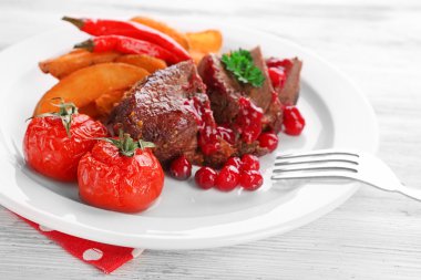 kızılcık sosu ve renk ahşap arka plan üzerinde plaka üzerinde kavrulmuş sebze ile lezzetli kavrulmuş et