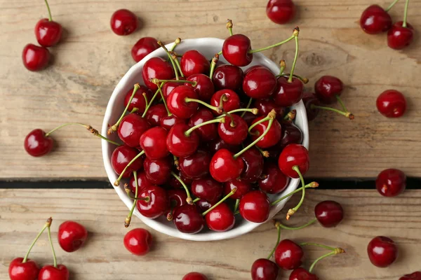 Sweet cherries in bowl on wooden table close up — Stock Photo, Image