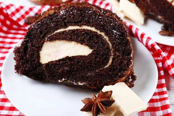 Délicieux rouleau de chocolat dans une soucoupe blanche sur une serviette à carreaux, gros plan — Photo