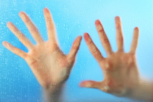 Женские руки за мокрым стеклом — стоковое фото