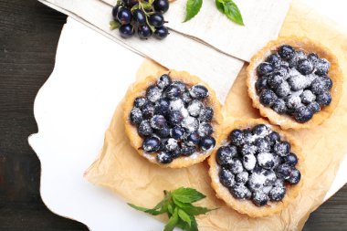 Ahşap masa, üstten görünüm üzerinde parşömen üzerine siyah kuş üzümü ile lezzetli çıtır tart
