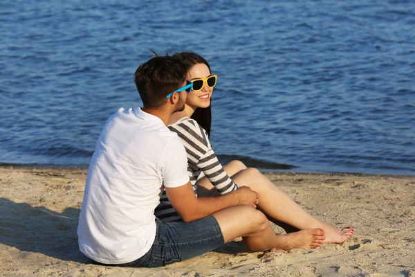 Jeune couple assis sur la plage — Photo