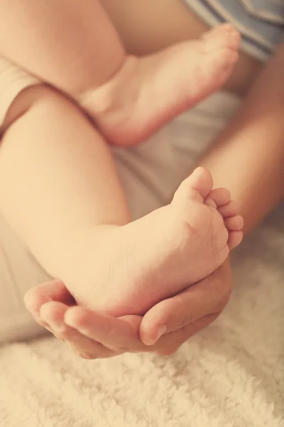 Vuxna händer som håller baby fötter — Stockfoto
