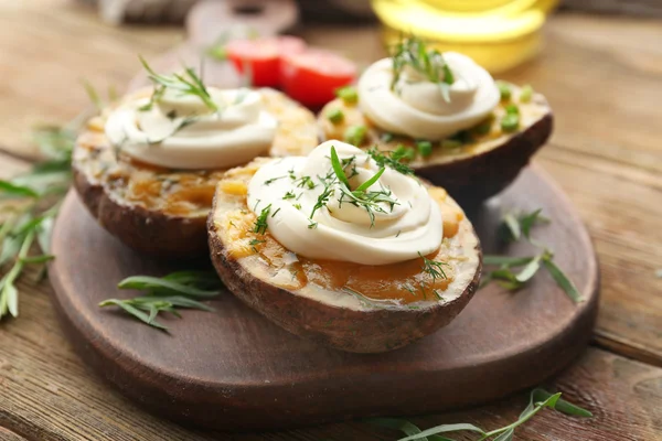 Backkartoffeln mit Mayonnaise und Kräutern auf Holzschneidebrett, Nahaufnahme — Stockfoto