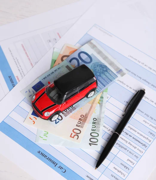 Coche de juguete, dinero y documentos en la mesa. Concepto de seguro de coche —  Fotos de Stock