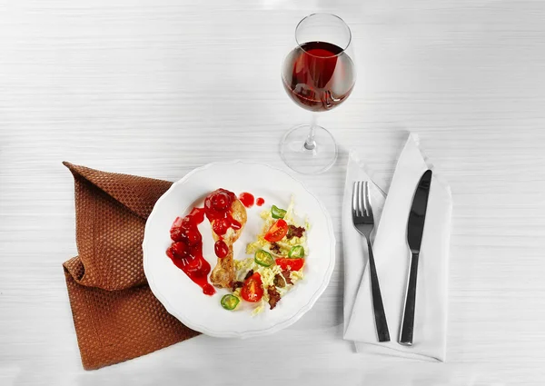 Prato de perna de frango assada e salada de legumes em placa branca com copo de vinho na mesa com guardanapo, close-up — Fotografia de Stock