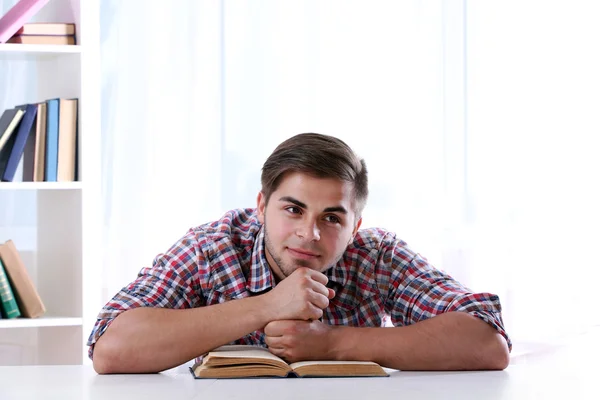 Jonge man leesboek aan tafel — Stockfoto