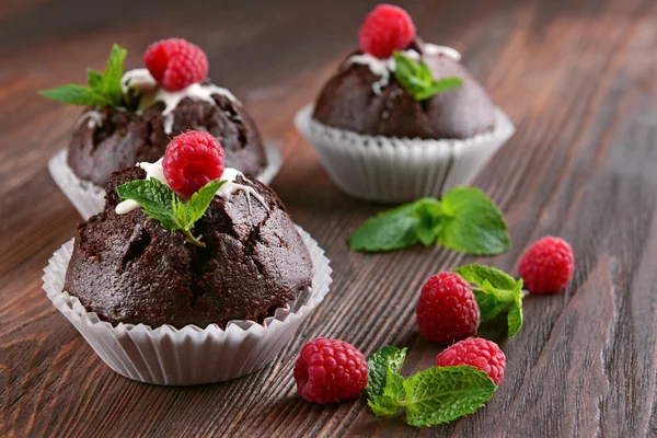 Leckere Schokoladen-Cupcakes mit Beeren und frischer Minze auf Holztisch aus nächster Nähe — Stockfoto