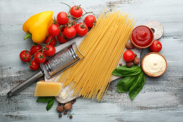 Nudelspaghetti mit Tomaten, Käse und Basilikum auf farbigem Holzhintergrund — Stockfoto