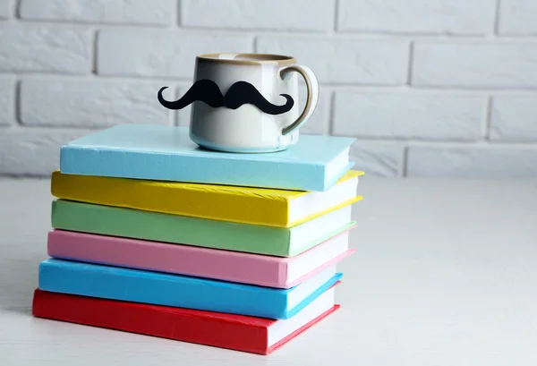 Böcker och cup med mustasch — Stockfoto