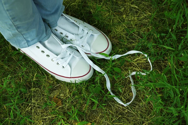 Pés femininos em sapatos de goma no fundo de grama verde — Fotografia de Stock