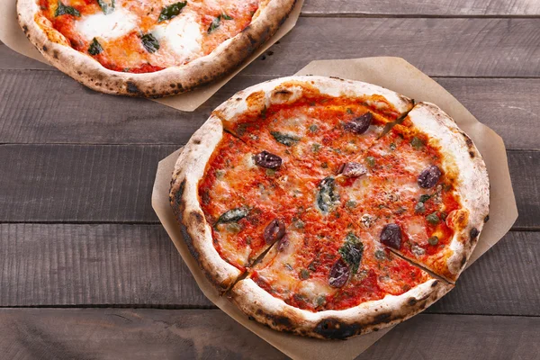 Deliciosas pizzas na mesa de madeira — Fotografia de Stock