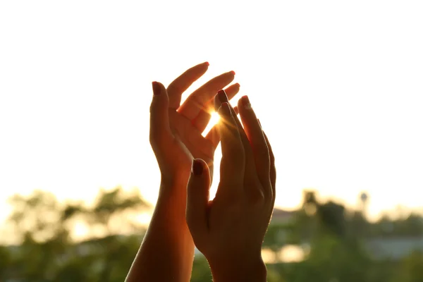 Mãos sobre o pôr do sol céu fundo — Fotografia de Stock