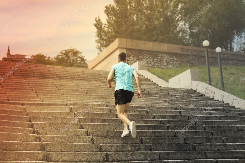 Young man jogging at stairs outdoors — Stock Photo © belchonock 79651454