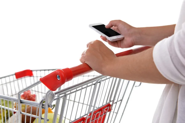 Young woman holding mobile phone and shopping cart — Stock Photo, Image