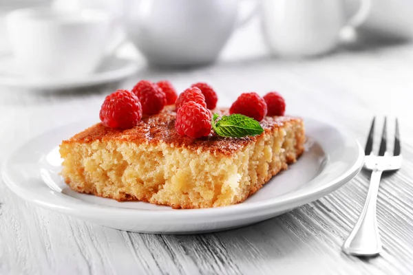 Pastel fresco con frambuesa en plato blanco sobre mesa de madera, primer plano —  Fotos de Stock